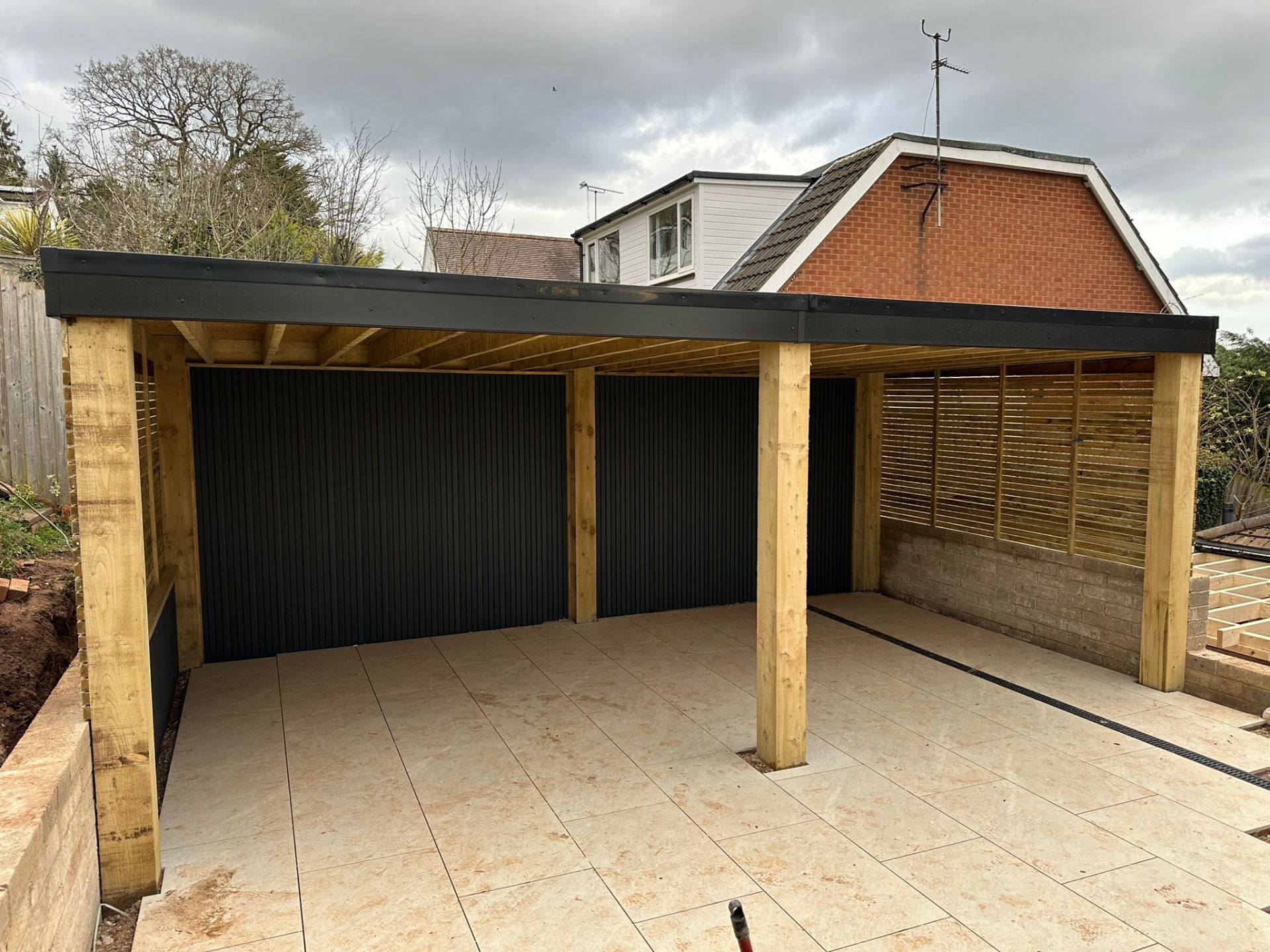 Timber-clad garden room with open carport bay and felt roof